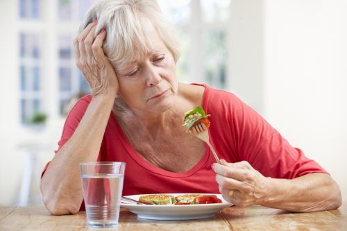 Sick older woman trying to eat